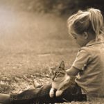 Little girl sitting outside, cat in her lap
