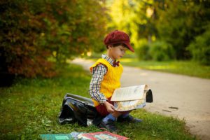 boy, yellow vest, sitting outside reading