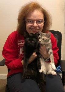 woman in red sweater holding 2 cats