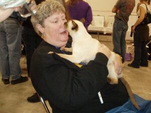 Woman holding cat who nips her nose