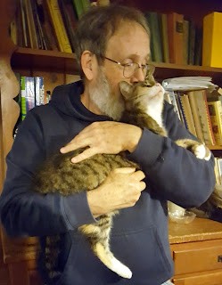 Man holding cat who is rubbing against face
