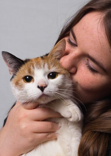 woman holding and kissing cat