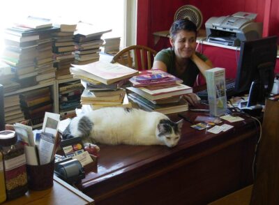 Cat on desk with woman and books